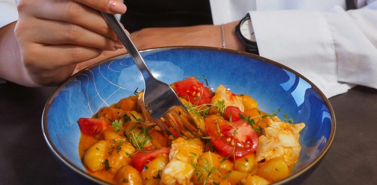 A young woman eats a colorful and healthy meal from a bowl, emphasizing balanced diet.