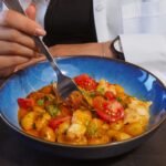 A young woman eats a colorful and healthy meal from a bowl, emphasizing balanced diet.
