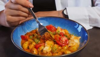A young woman eats a colorful and healthy meal from a bowl, emphasizing balanced diet.