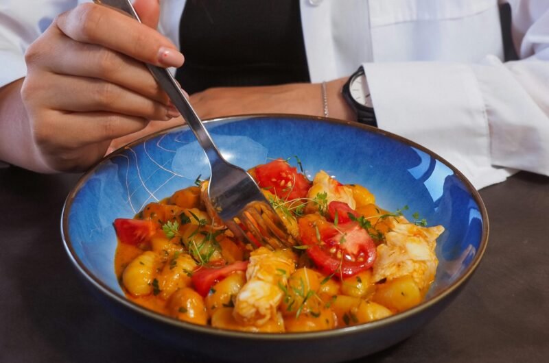 A young woman eats a colorful and healthy meal from a bowl, emphasizing balanced diet.