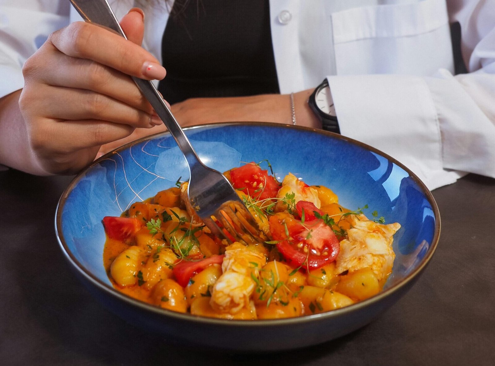 A young woman eats a colorful and healthy meal from a bowl, emphasizing balanced diet.