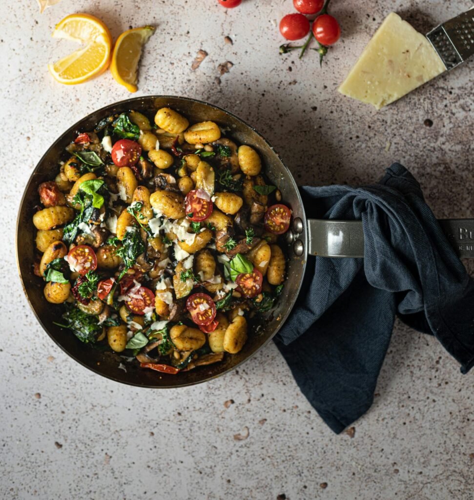 Delicious chicken and gnocchi soup recipe with fresh basil, cherry tomatoes, and cheese in a rustic setting. 