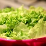 A close-up shot of fresh green lettuce leaves in a vibrant pink bowl, perfect for salads.