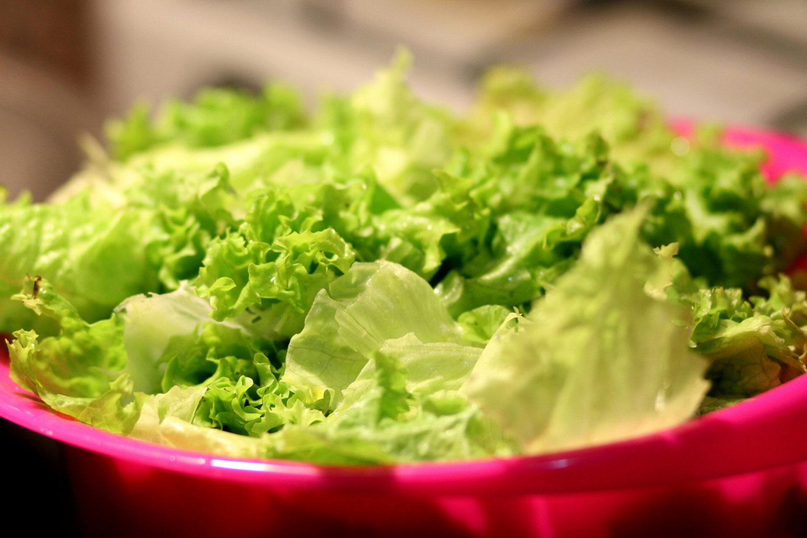 A close-up shot of fresh green lettuce leaves in a vibrant pink bowl, perfect for salads.