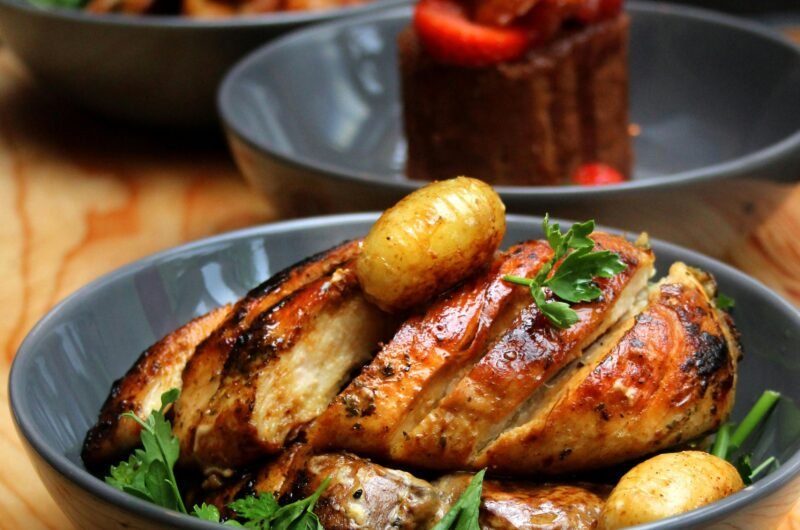Delicious roasted chicken breast with potatoes and fresh salad in elegant bowls.