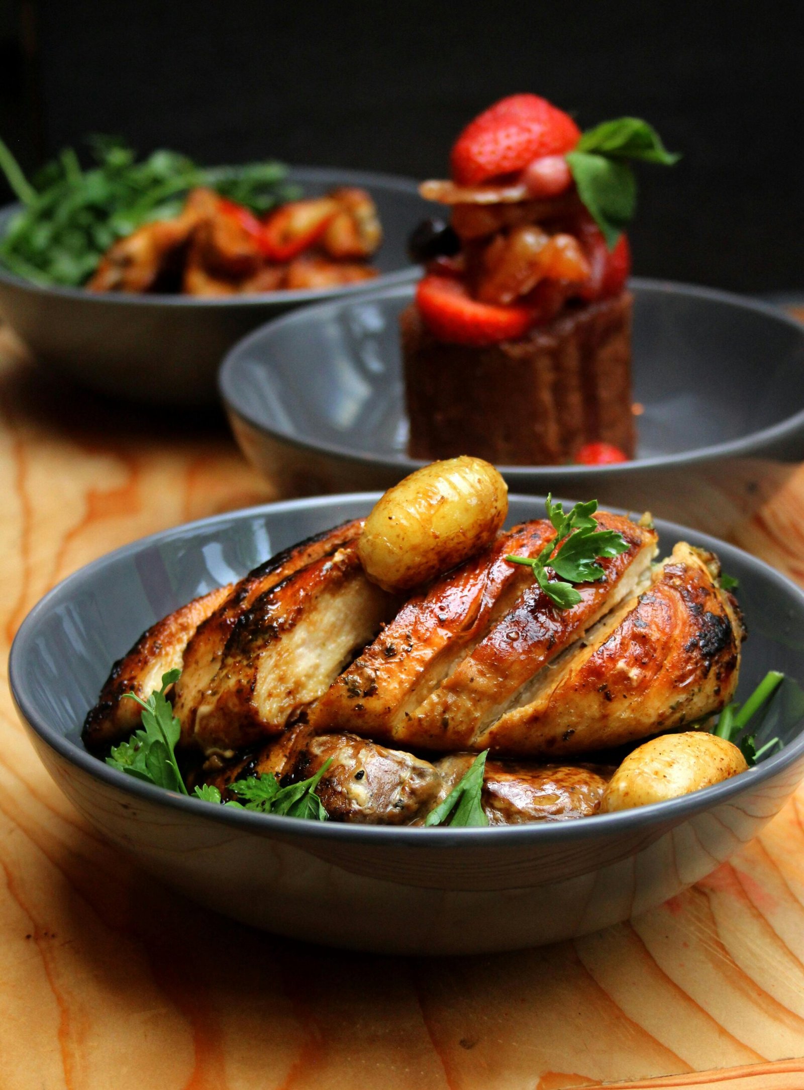 Delicious roasted chicken breast with potatoes and fresh salad in elegant bowls.