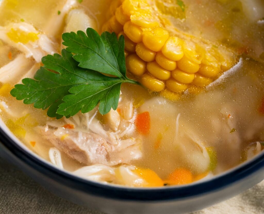 Warm chicken soup with corn, carrot, and parsley, perfect for comforting meals.
