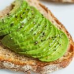 Sliced avocado atop sourdough bread, seasoned with pepper, photographed for a food photography series.