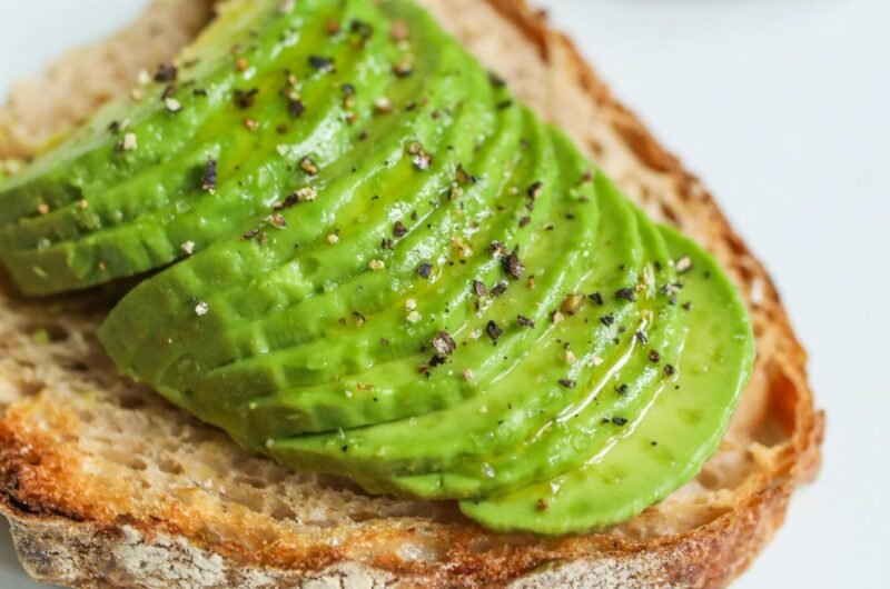 Sliced avocado atop sourdough bread, seasoned with pepper, photographed for a food photography series.
