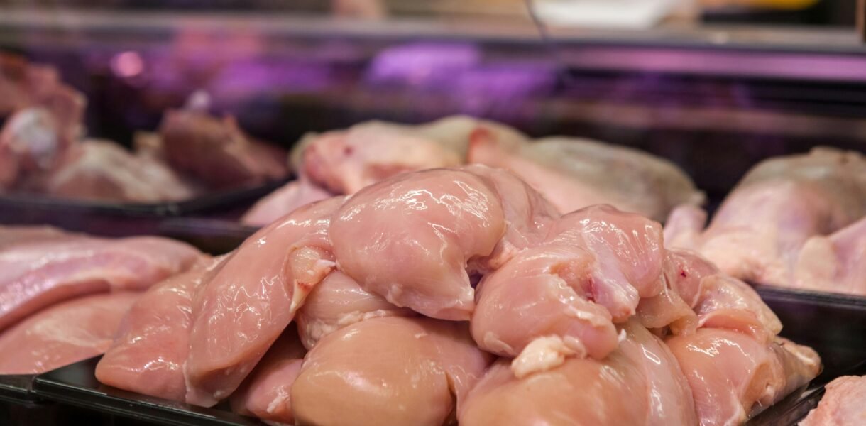 Fresh raw chicken breasts displayed in a supermarket setting, ready for purchase.