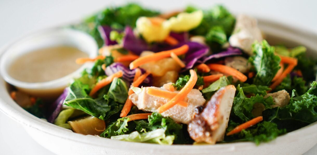 Close-up of a vibrant and healthy mixed green salad with chicken and dressing, perfect for a nutritious meal.