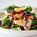 Close-up of a vibrant and healthy mixed green salad with chicken and dressing, perfect for a nutritious meal.