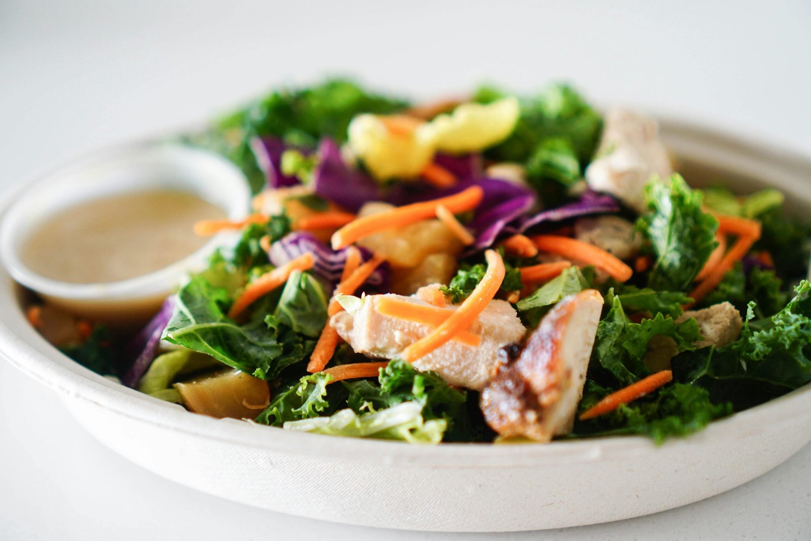 Close-up of a vibrant and healthy mixed green salad with chicken and dressing, perfect for a nutritious meal.
