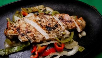 Succulent grilled chicken with vibrant peppers on a sizzling plate, perfect for a tasty meal.