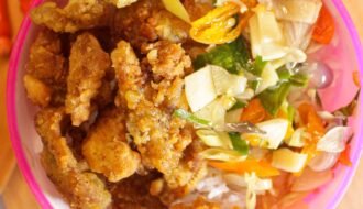 Indonesian crispy fried chicken served with salad on a wooden board.