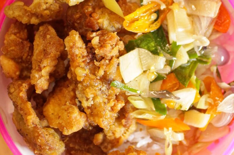 Indonesian crispy fried chicken served with salad on a wooden board.